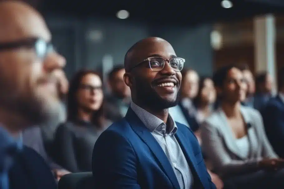 Professional Black male smiling in a audience or business conference setting.