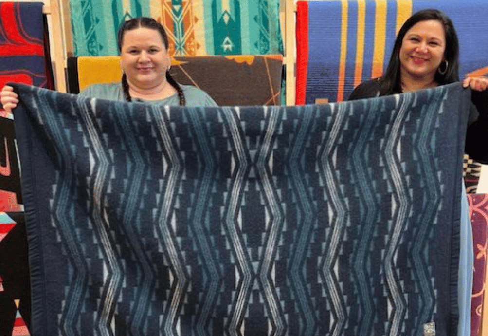 Kendra Lowden and colleague hold up an Indigenous blanket.