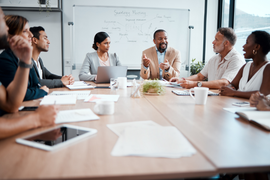 A group of professionals sitting at a table during a meeting in a brightly lit office.